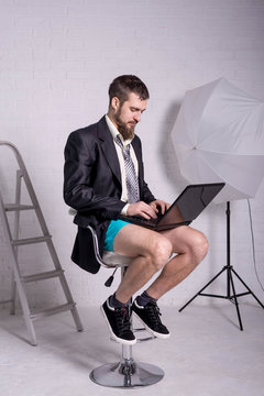Man in a jacket and shorts is sitting with a laptop, the concept of remote work.