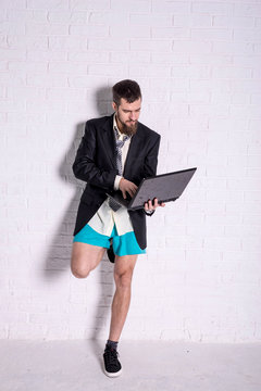 Business man in a jacket and shorts working on the laptop remotely.