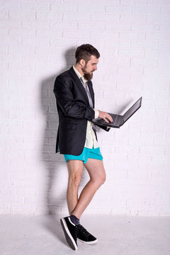 Business man in a jacket and shorts working on the laptop remotely.