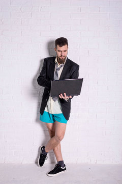 Business man in a jacket and shorts working on the laptop remotely.