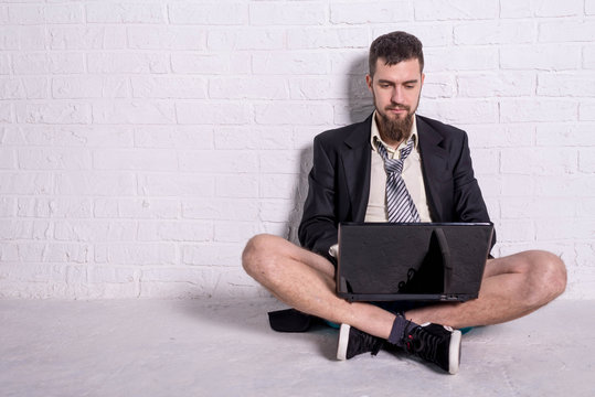 Business man in a jacket and shorts working on the laptop remotely. Workaholic working on weekends.