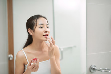 Pretty asian woman putting balm on lips.