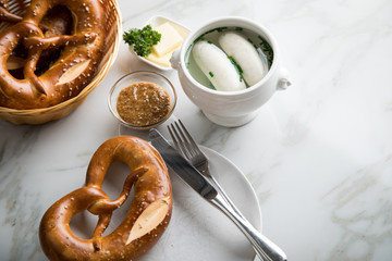 Münchener Weißwurst in Terrine mit bayrischer süßen Senf, Brezel und Butter auf Marmor Tisch