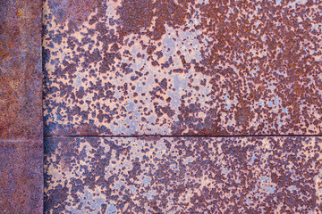 two sheets of rusty metal welded together lie on each other.