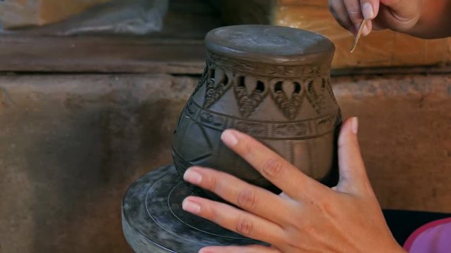 Hands make potter inflicts a decorative pattern on earthenware