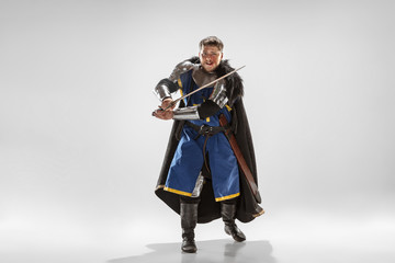 Brave armored knight with professional weapon fighting isolated on white studio background. Historical reconstruction of native fight of warriors. Concept of history, hobby, antique military art.