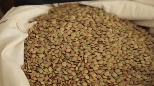 Multigrain horsegram grains stacked in a gunny bag, panning closeup