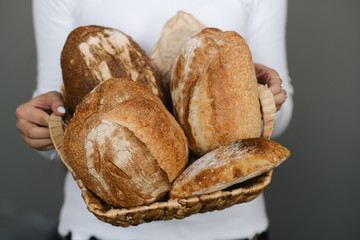 Woman holding a loaf of bread in a wicker basket. Close-up of a woman holding a loaf of homemade bread.