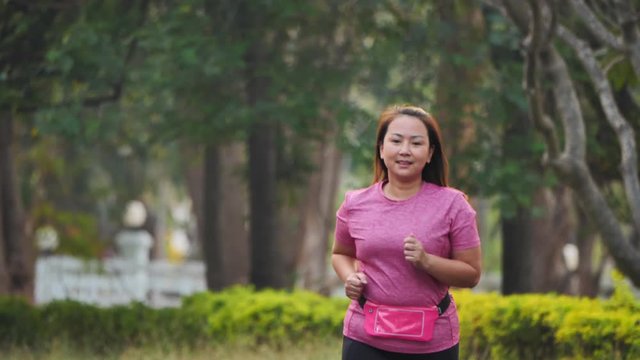 Asian woman jogging exercise on the road in the park. Front view Female running in the evening. Health and fitness. Slow Motion