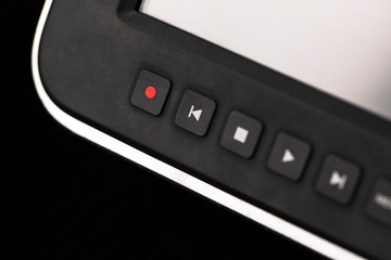 close-up video camera control buttons and screen on blurred black background