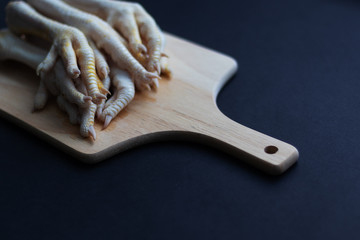 Raw chicken legs lie on a cutting board. A healthy organic product for keto, diets and a healthy diet. Black background. Ingredients for jelly food. Horizontal orientation and copy space