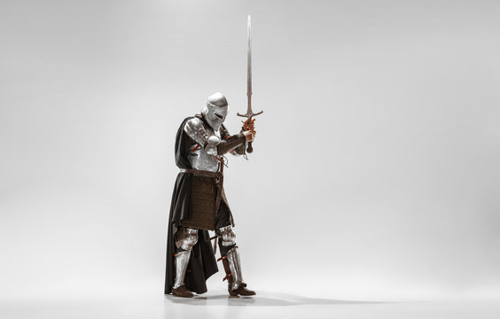 Brave armored knight with professional weapon fighting isolated on white studio background. Historical reconstruction of native fight of warriors. Concept of history, hobby, antique military art.