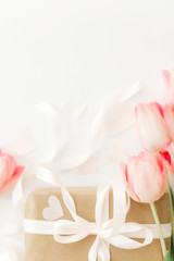 Obraz na płótnie Canvas Pink tulips with ribbon and gift box on white background, flat lay. Stylish vertical image. Happy womens day. Greeting card with space for text. Happy Mothers day. Wedding or valentine mockup