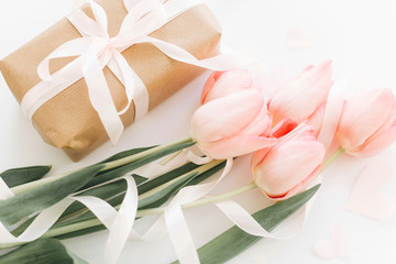 Obraz na płótnie Canvas Pink tulips with ribbon and gift box on white background. Stylish soft image of spring flowers. Happy womens day. Greeting card mockup. Happy Mothers day. Hello spring