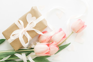 Fototapeta na wymiar Pink tulips flat lay with ribbon and gift box on white background. Stylish soft image of spring flowers. Happy womens day. Greeting card mockup. Happy Mothers day. Hello spring