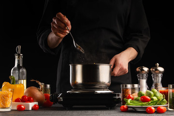 The chef cooks a soup with vegetables. Salts, freezing in motion. Culinary and cooking. Delicious and proper nutrition. Gastronomy, restaurant business or hotel business.