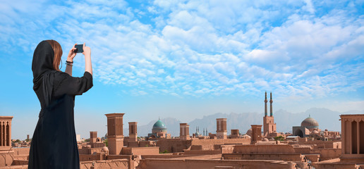 Beautiful Iranian girl wearing abaya with taking selfie - Historic City of Yazd with famous wind towers - YAZD, IRAN