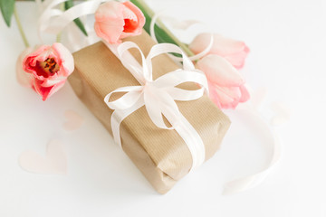 Pink tulips with ribbon and gift box on white background. Stylish soft image of spring flowers. Happy womens day. Greeting card mockup. Happy Mothers day.  Hello spring