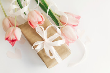 Obraz na płótnie Canvas Happy Mothers day. Pink tulips flat lay with ribbon and gift box on white background. Stylish soft image of spring flowers. Happy womens day. Greeting card mockup. Hello spring