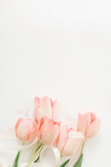 Fototapeta na wymiar Happy womens day. Pink tulips with ribbon and hearts on white background, flat lay. Stylish soft vertical image. Greeting card mockup with space for text. Happy Mothers day. Valentines day