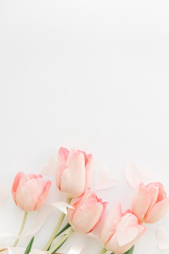 Happy Mothers day. Pink tulips with ribbon and hearts on white background, flat lay. Stylish soft vertical image. Happy womens day. Greeting card mockup with space for text.  Valentines day