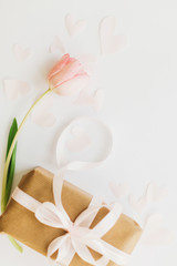 Obraz premium Pink tulip flat lay and gift box with ribbon on white background, space for text. Stylish vertical image. Happy womens day. Greeting card mockup. Happy Mothers day. Hello spring