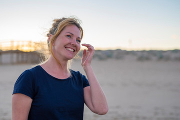 Fototapeta premium Young attractive white caucasian woman smiling and laughing on the beach warm summer evening