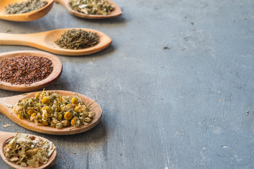 herbs with wooden spoon in gray slate background