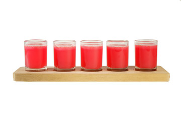 Red, same color transparent cocktails, a set of shots in one row, five servings on a wooden stand, substrate. Side view Isolated white background. Drink for the menu restaurant, bar, cafe