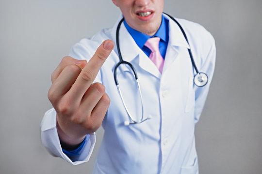 Aggressive rude angry young doctor shows an impolite middle index finger gesture of derision and dismissal