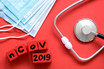 Red cubes with nCoV 2019 text, a stethoscope and an ampoule on red background. Defeating...
