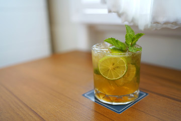 A glass of Mojito cocktail - Made with lime, mint, cane sugar and soda on blurred background and...