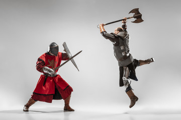 Brave armored knights with professional weapon fighting isolated on white studio background. Historical reconstruction of native fight of warriors. Concept of history, hobby, antique military art. - obrazy, fototapety, plakaty