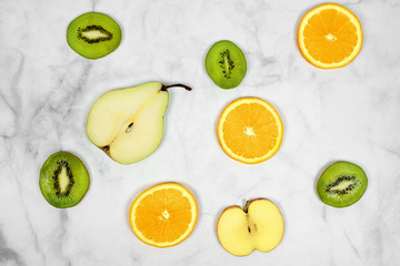 sliced fruits pear kiwi orange apple with minimalist marble background