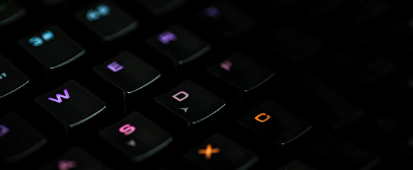 ..A gaming keyboard with rgb color backlight shot closeup on a black background with space for...
