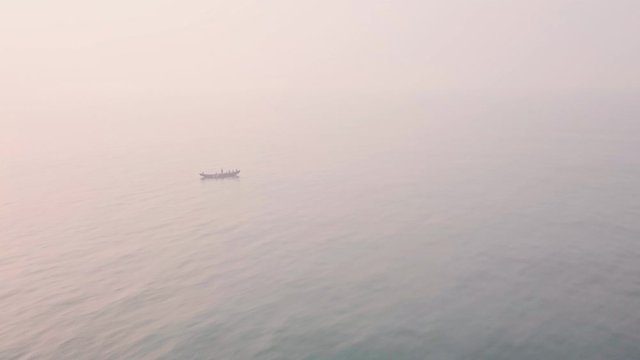 Fishing boat at sea at sunrise, net fishing. Aerial drone view