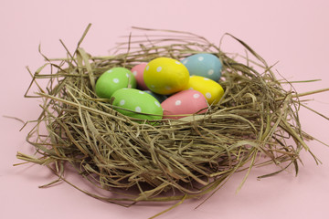 Colorful Easter egg in a nest on a pink background