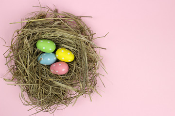 Colorful Easter egg in a nest on a pink background