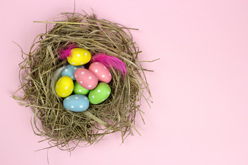 Colorful Easter egg in a nest on a pink background
