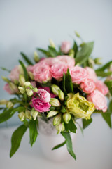 Bright bouquet with roses, eustoma and alstroemeria in white vase. Bouquet on soft blue background
