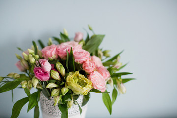 Bright bouquet with roses, eustoma and alstroemeria in white vase. Bouquet on soft blue background