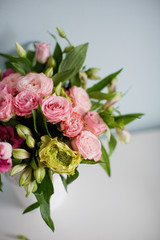 Bright bouquet with roses, eustoma and alstroemeria in white vase. Bouquet on soft blue background