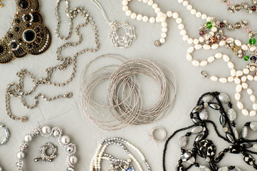 Jewelry on a gray background. Women's fashion accessories in the form of jewelry. Silver bracelets, pearl beads on a textured background. A lot of jewelry.