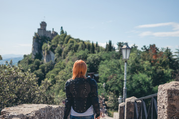 Woman dressed in a motorcycle outfit and sunglasses. body protection turtle and knee pads, helmet in hand. Fortress, stone steps, stairs. Journey, vacation. Pass of the witches San Marino