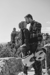 Romantic couple are kissing. Dressed in a motorcycle outfit. body protection turtle and knee pads, helmet in hand. Fortress on background. Vertical photo. Black and white. San Marino