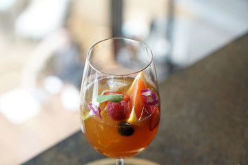 Iced black coffee with fresh juice - A glass of cold brew coffee with mandarin orange, ginger, lemon and mixed fruit on blurred background, Perfect drink for summer time.