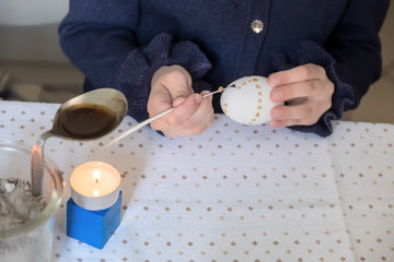 Child hand paints an Easter egg after sorbian tradition with goose feather and candle wax.