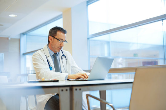 Doctor In Hospital Office Working On Laptop