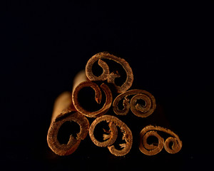 six closeup cinnamon sticks laid out by a triangle on a black blurred background