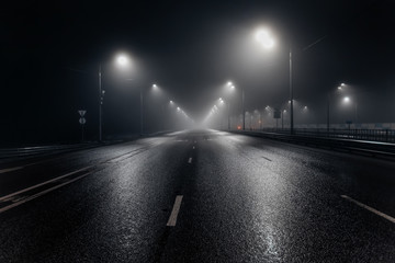 Foggy misty night road illuminated by street lights